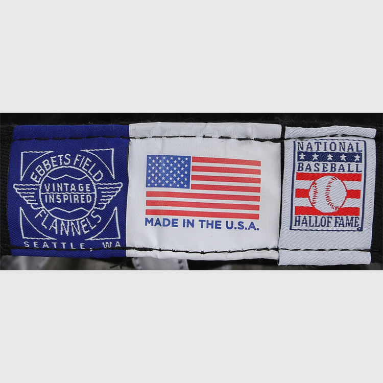 Three fabric labels: one reads Ebbets Field Flannels, the center shows a U.S. flag with MADE IN THE U.S.A., and the third honors the National Baseball Hall of Fame on this Bob Gibson Signature Series Ballcap.