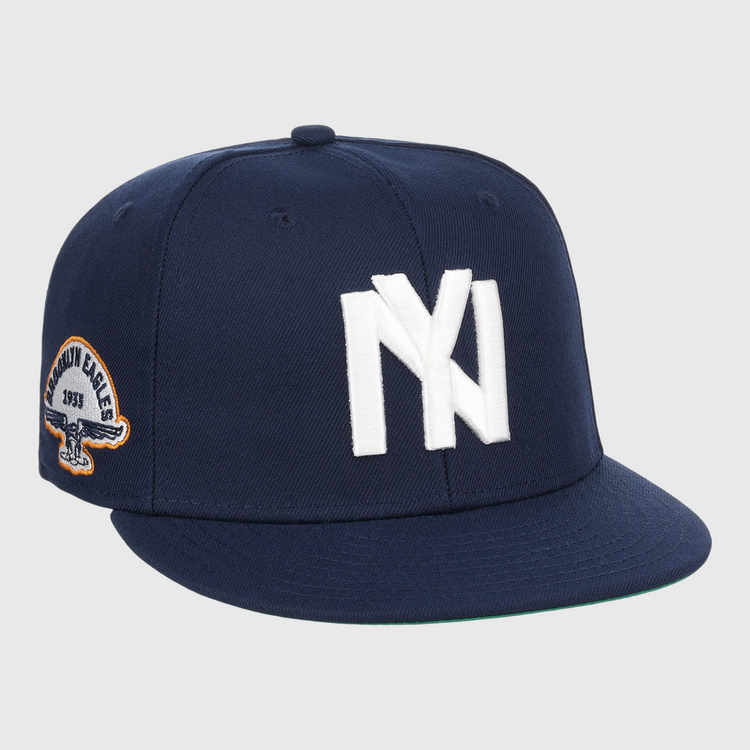 The EFF Brooklyn Eagles NLB Team Color Fitted Ballcap is a navy blue cap with a bold white NY logo on the front and a side eagle patch displaying 1993 and BKLYN EAGLES.