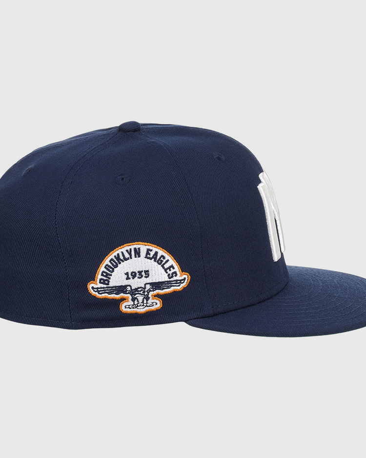 The EFF Brooklyn Eagles NLB Team Color Fitted Ballcap features a navy blue flat-brim design with bold NY embroidery up front and a 1935 Brooklyn Eagles patch with eagle logo on the side, perfect for collectors seeking vintage style.