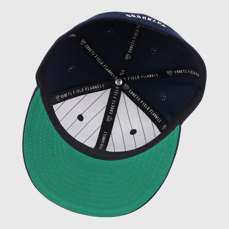 A navy Brooklyn Eagles NLB Team Color Fitted Ballcap by EFF, seen from below with a green underbrim, black and white pinstriped lining, and EBBETS FIELD FLANNELS printed on the inner seams.