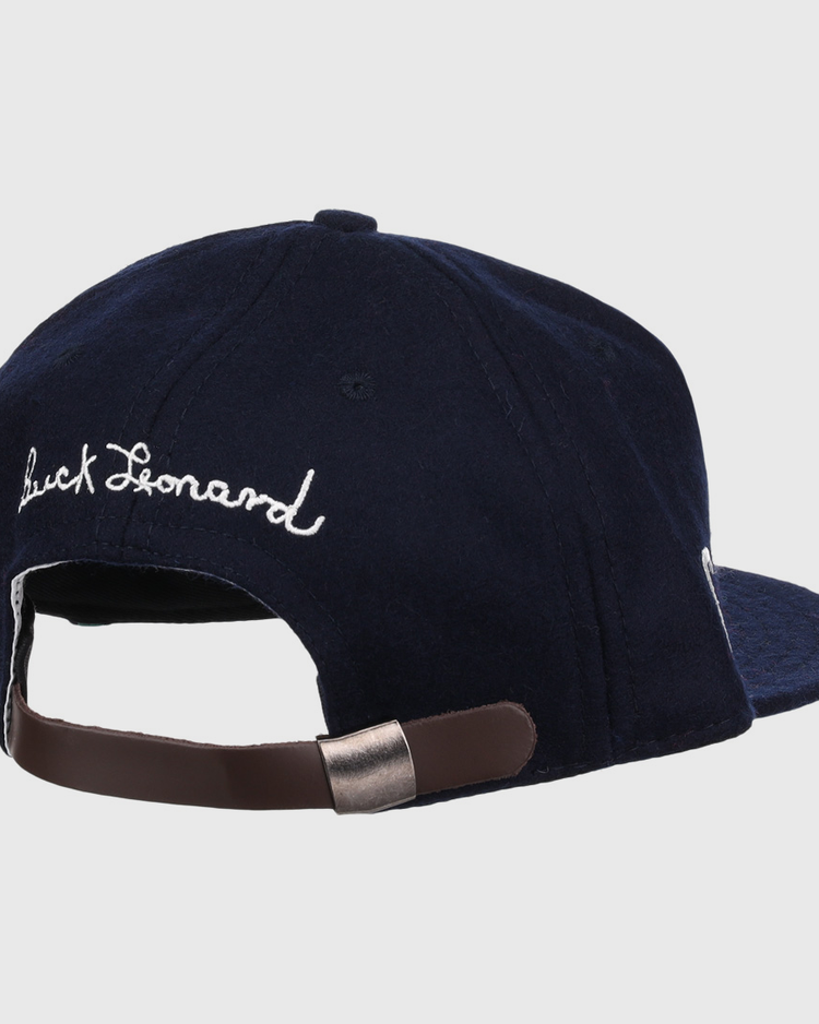 The Buck Leonard Signature Series Ballcap by Ebbets Field Flannels is a navy vintage wool cap seen from the back, with white cursive Buck Leonard embroidery and an adjustable brown strap with metal clasp honoring the Negro Leagues legend.