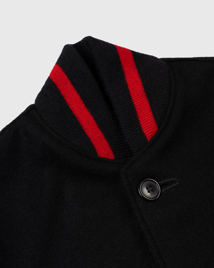 Close-up of the EFF Birmingham Black Barons 1940 Authentic All Wool Varsity Jacket in black, showcasing a ribbed collar with two red stripes and a black front button, set against a light grey background.