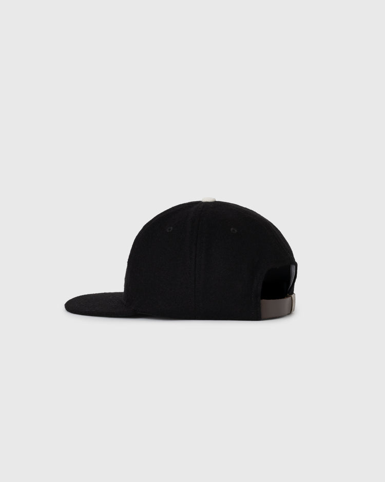 A side view of the EFF Fuji Athletic Club 1931 Authentic Wool Ballcap in black, with a rounded crown, flat brim, and adjustable strap—an homage to Japanese-American baseball—set against a plain gray background.