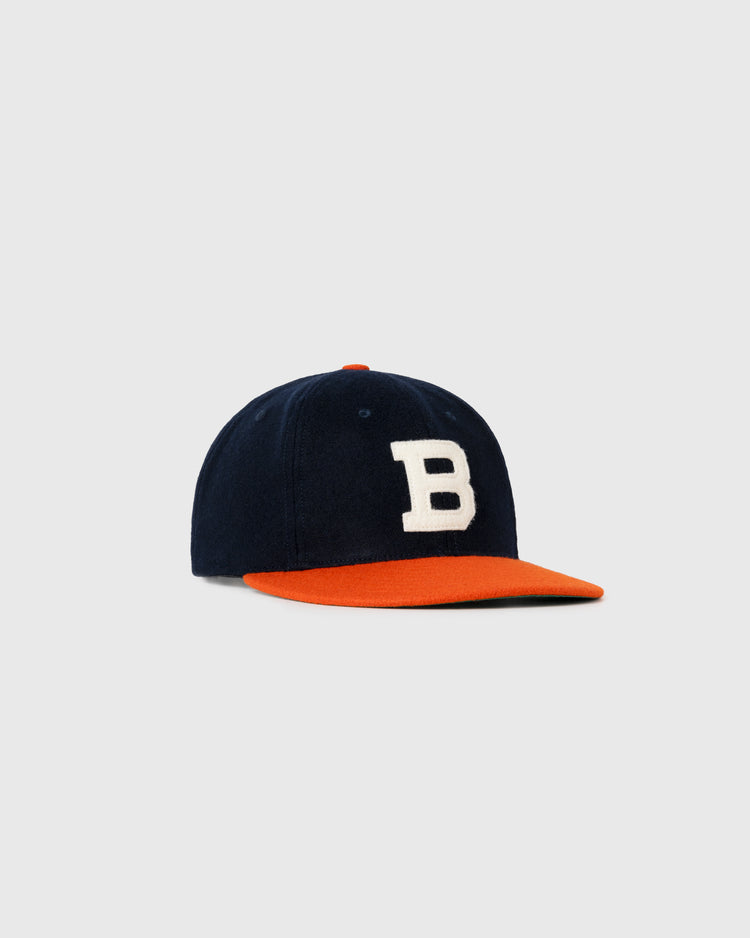 The EFF Brooklyn Bushwicks 1949 Authentic Wool Ballcap features navy wool, a white B on the front, and a bright orange brim—reflecting Brooklyn baseball history. Shown against a plain gray background.