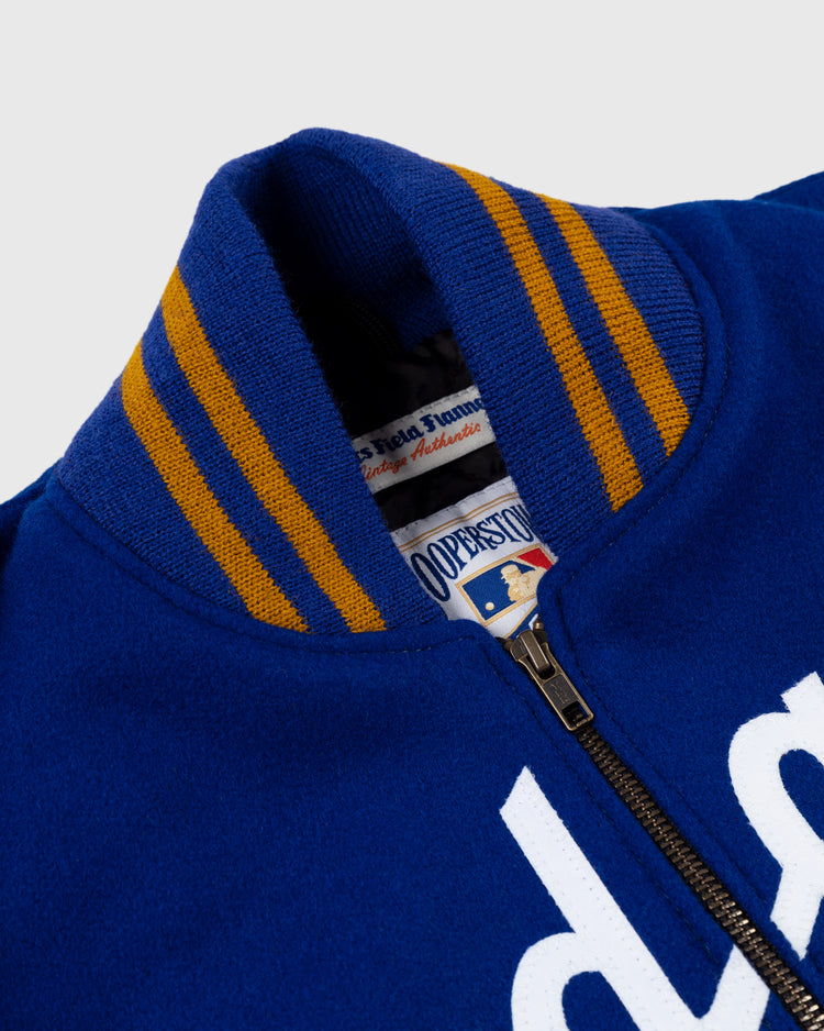 Close-up of an EFF Brooklyn Dodgers 1951 Authentic Wool & Leather Varsity Jacket in blue, featuring a yellow-striped ribbed collar, visible zipper, and partial “Cooperstown” label. White lettering hints at its classic team era heritage.