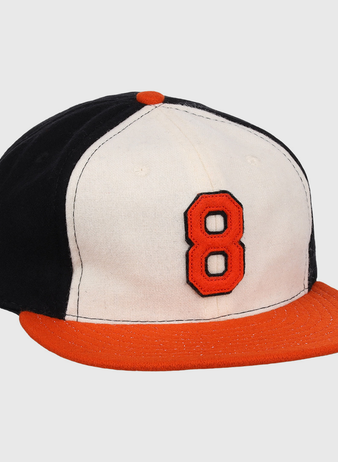 The Ebbets Field Flannels Cal Ripken Jr. Signature Series Ballcap features a vintage design with a black back, white front, orange brim and button, plus a bold orange number 8 outlined in black as tribute to Cal Ripken Jr.