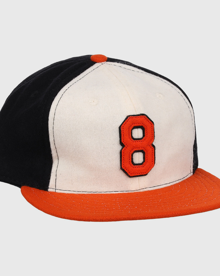 The Ebbets Field Flannels Cal Ripken Jr. Signature Series Ballcap features a vintage design with a black back, white front, orange brim and button, plus a bold orange number 8 outlined in black as tribute to Cal Ripken Jr.