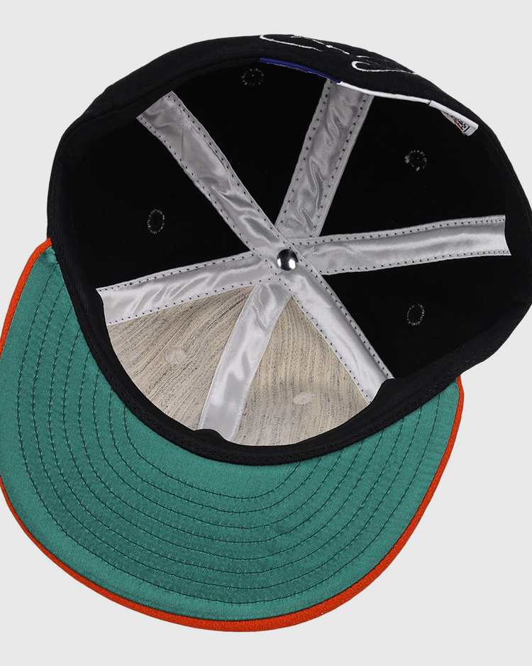 An overhead view of the Cal Ripken Jr. Signature Series Ballcap by Ebbets Field Flannels, featuring a green brim with an orange edge, visible inner stitching, silver panels, and a round button at the crown.