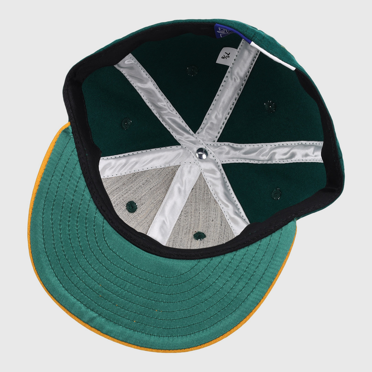Inside view of the Ebbets Field Flannels Catfish Hunter Signature Series Ballcap, featuring a green crown, yellow brim, white stitching, fabric tag, and six ventilation holes.