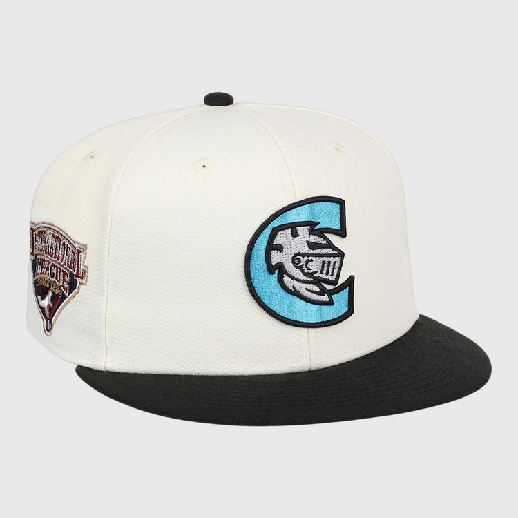 The Ebbets Field Charlotte Knights MiLB Snapback Ballcap is a white cap with a black brim, a large blue and black C logo with a fish and Roman numerals on the front, plus a brown Continental League patch on the side.