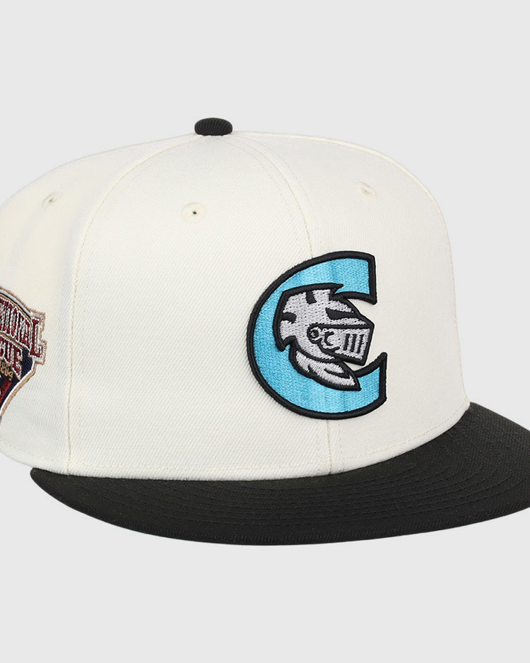 The Ebbets Field Charlotte Knights MiLB Snapback Ballcap is a white cap with a black brim, a large blue and black C logo with a fish and Roman numerals on the front, plus a brown Continental League patch on the side.
