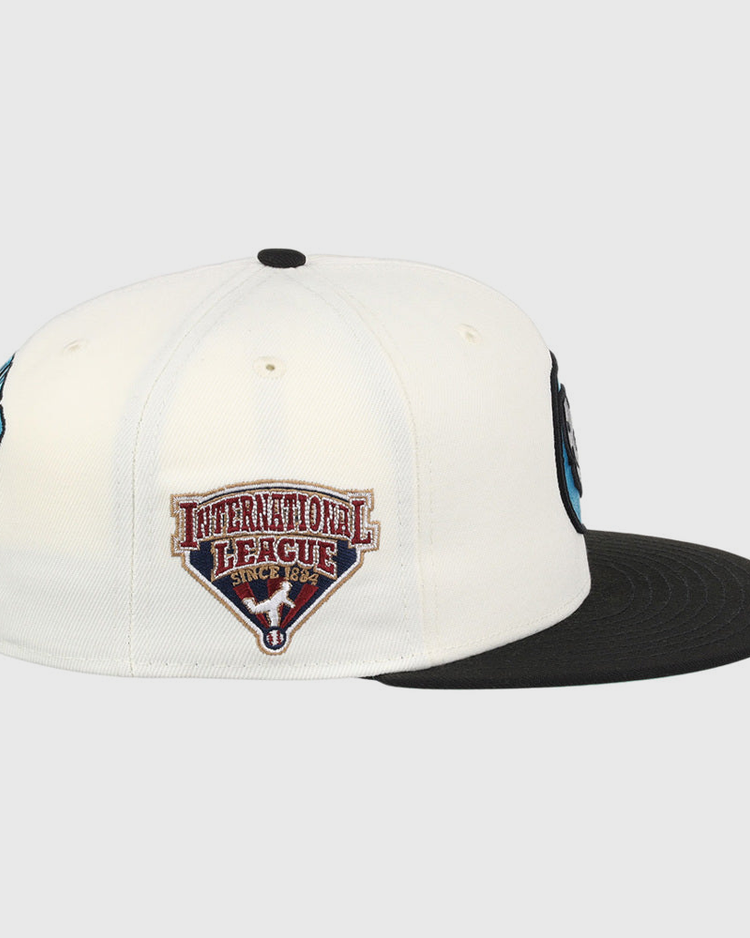 The Ebbets Field Charlotte Knights MiLB Snapback Ballcap is a black and white cap, shown from the side, featuring an International League Since 1884 patch with a red and white shield on the side panel.