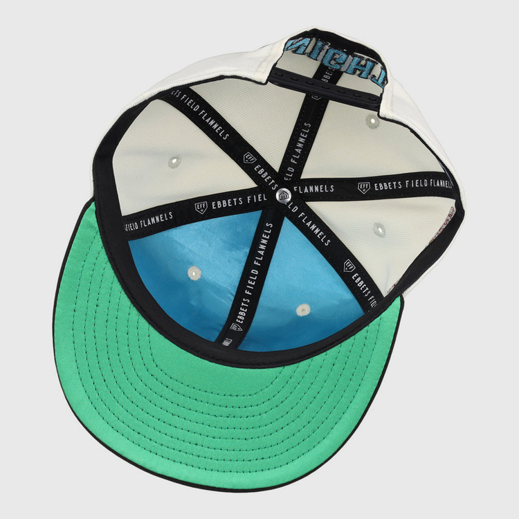 The underside of the Charlotte Knights MiLB Snapback Ballcap by Ebbets Field features a green brim, blue crown lining, black taping with “EBBETS FIELD FLANNELS” in white text, plus white eyelets and stitching inside.
