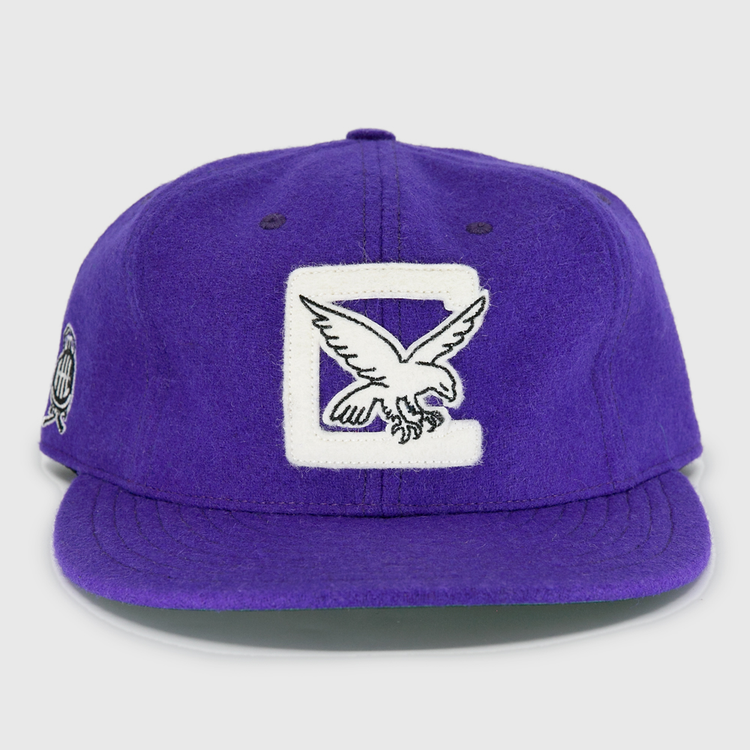 The EFF Cleveland Falcons 1936 Vintage Ballcap is a purple wool cap featuring a large white C and embroidered falcon on the front, a circular patch on the left side, and an adjustable leather strap for a perfect fit.