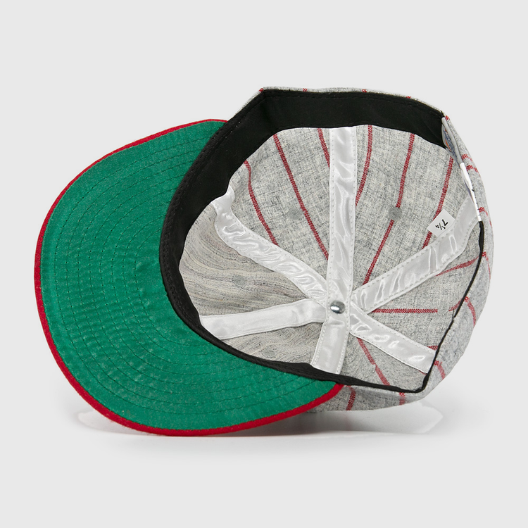 An overhead shot of the Ebbets Field Flannels Club Artemisa 1943 Vintage Ballcap, a wool cap with red stripes, green underside brim, and white interior seams. The hat is shown upside down to highlight its inner structure and tag.