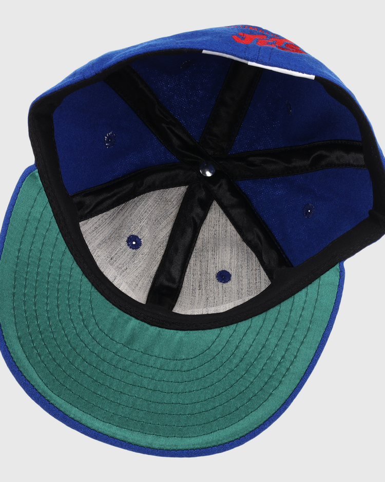 The EFF Columbus Jets Letterhead Wool Vintage Ballcap features a blue wool build, green brim, black inner seams, grey panels, and a white inner tag—capturing the classic style of vintage Minor League baseball caps.