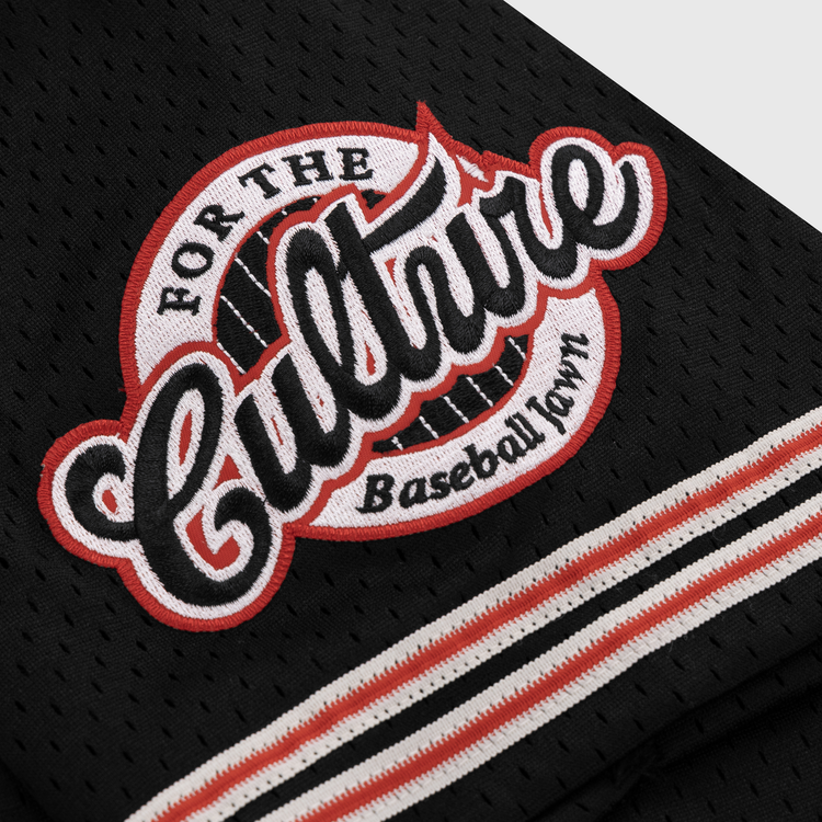 A close-up of the EFF Cultural Excellence x Philadelphia Stars Button Down Jersey shows black mesh fabric with a patch reading “For The Culture Baseball Town,” in bold white and red letters, inspired by Negro League Baseball, with striped black, white, and red trim.
