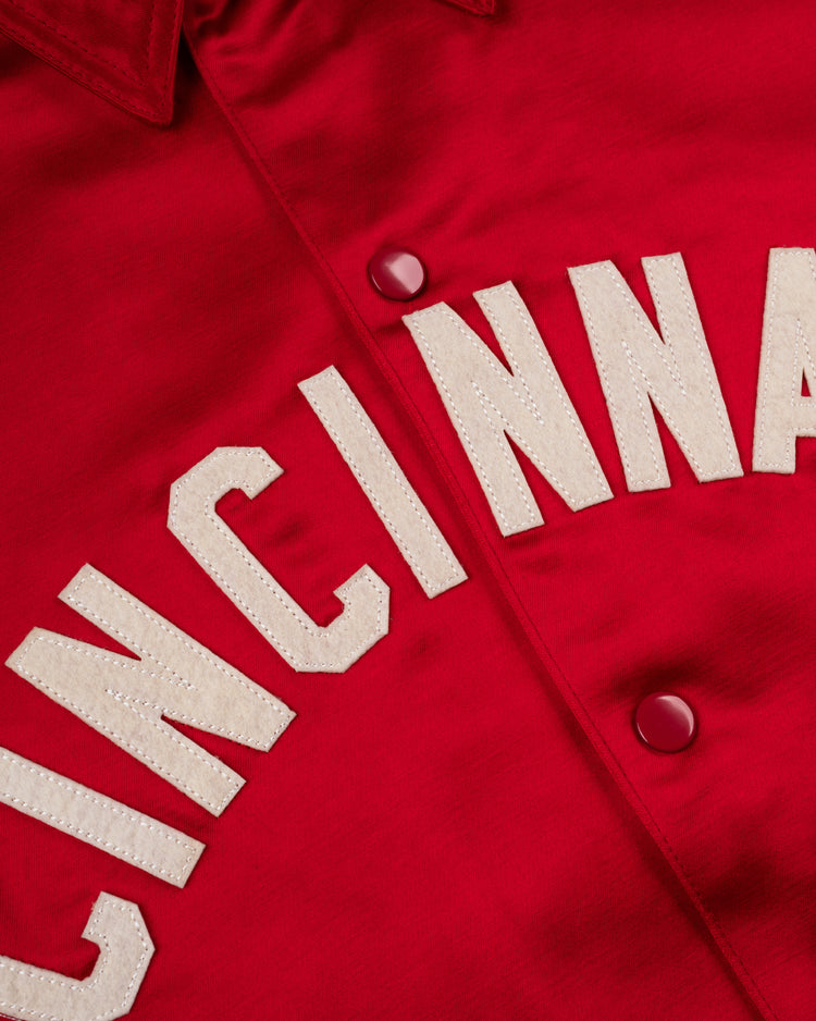 Close-up of the EFF Cincinnati Reds 1955 Satin Windbreaker Jacket, featuring smooth red satin, bold white CINCINNATI lettering, and matching red buttons—a true vintage MLB classic.