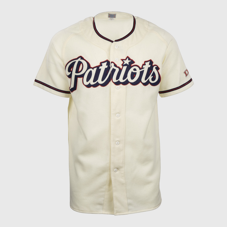 The EFF Dallas Baptist University Home Jersey is cream-colored with black and red trim, Patriots in large script on the chest, a flannel-style design, front buttons, and short sleeves.