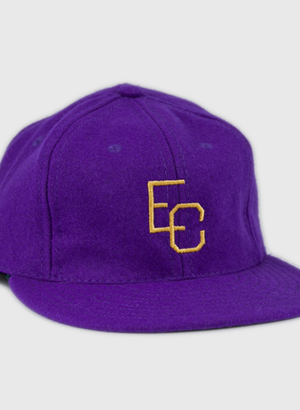The Ebbets Field Flannels East Carolina University 1961 Vintage Ballcap is a purple wool cap with interlocking yellow EC letters on the front, shown at a slight angle against a white background.