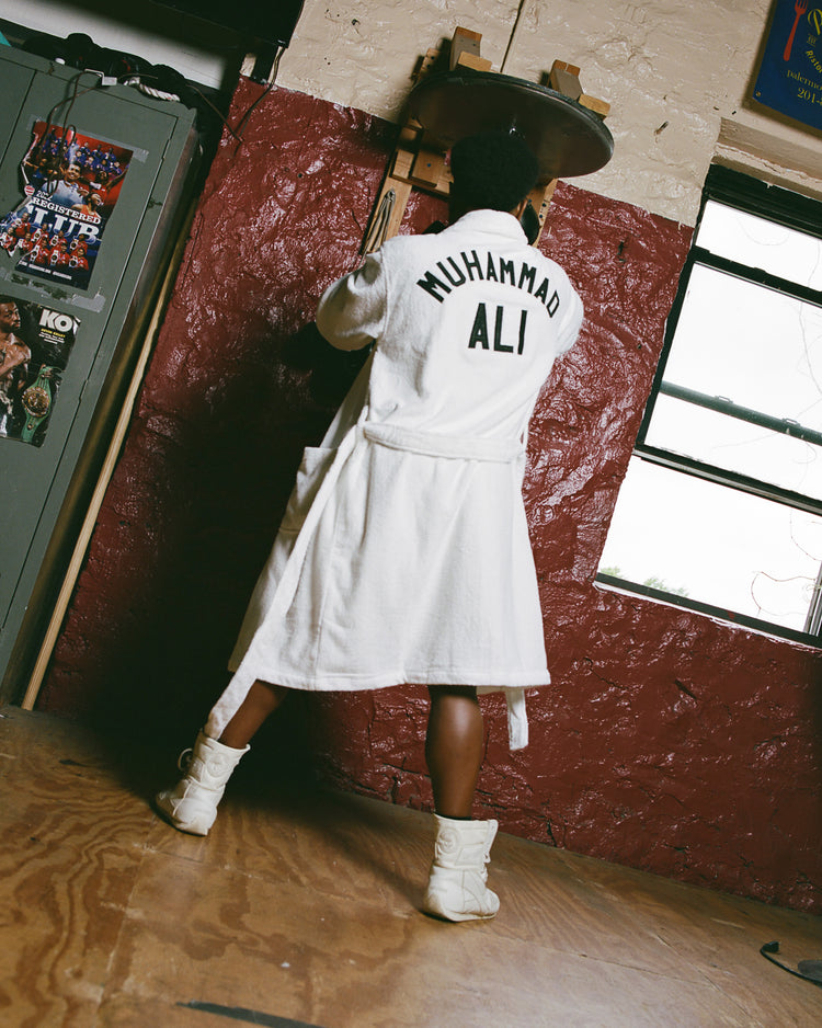 Wearing an Ebbets Field Muhammad Ali Cotton Terry Boxing Robe, a person with 