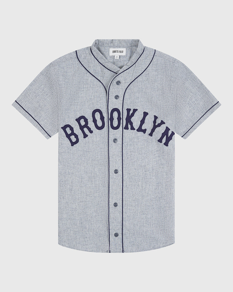 Crafted by Ebbets Field, the Brooklyn Eagles 1935 Authentic Wool Road Jersey features a gray short-sleeve button-up design with black piping and bold black “BROOKLYN” lettering across the chest, faithfully reproducing the classic Negro Leagues style—an ideal piece for any baseball enthusiast.