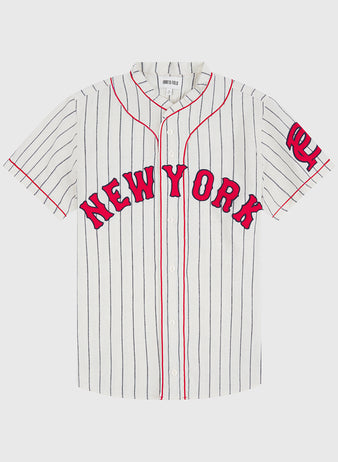 The Ebbets Field New York Cubans 1935 Authentic Wool Road Jersey features a white, short-sleeve design with thin black vertical stripes, red piping, “NEW YORK” in red letters on the front, and a red NY logo on the left sleeve—capturing the iconic style of classic Negro League jerseys.