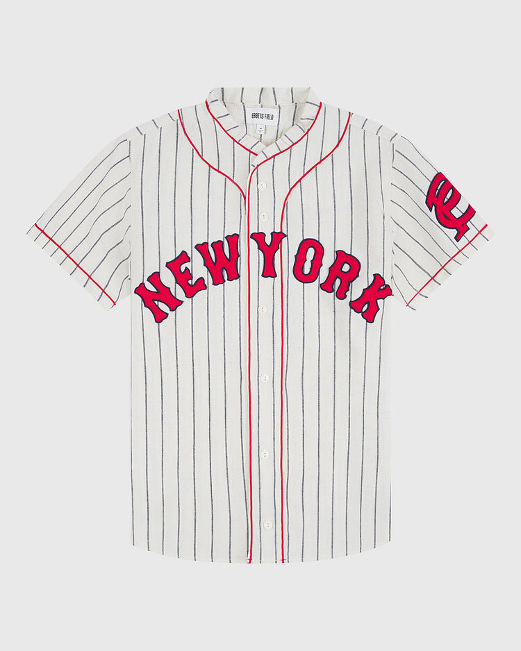 The Ebbets Field New York Cubans 1935 Authentic Wool Road Jersey features a white, short-sleeve design with thin black vertical stripes, red piping, “NEW YORK” in red letters on the front, and a red NY logo on the left sleeve—capturing the iconic style of classic Negro League jerseys.