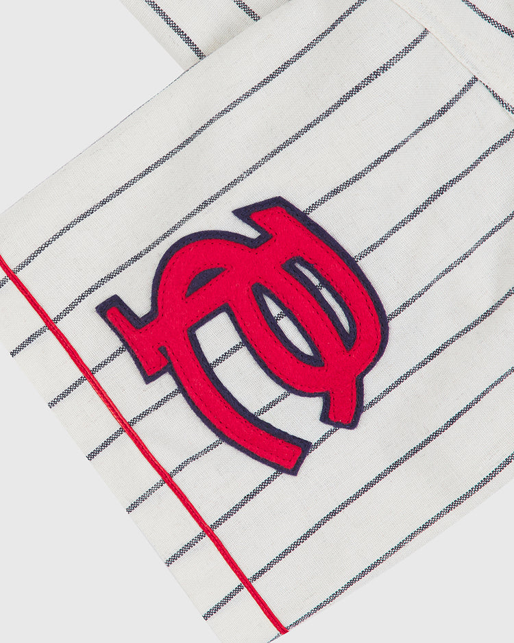 A close-up of the Ebbets Field New York Cubans 1935 Authentic Wool Road Jersey, featuring white wool fabric with thin black stripes, red trim, and a bold red and navy blue embroidered monogram logo—faithfully inspired by the iconic style of the 1935 New York Cubans Negro League jersey.