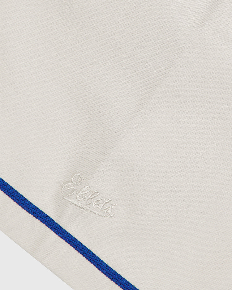 A close-up of the Ebbets Field Brooklyn Royal Giants 1919 Cotton Twill Baseball Jersey, featuring a cream-colored cotton twill fabric, “Ebbets” embroidered in white thread, and a blue and purple stripe accenting the edge.