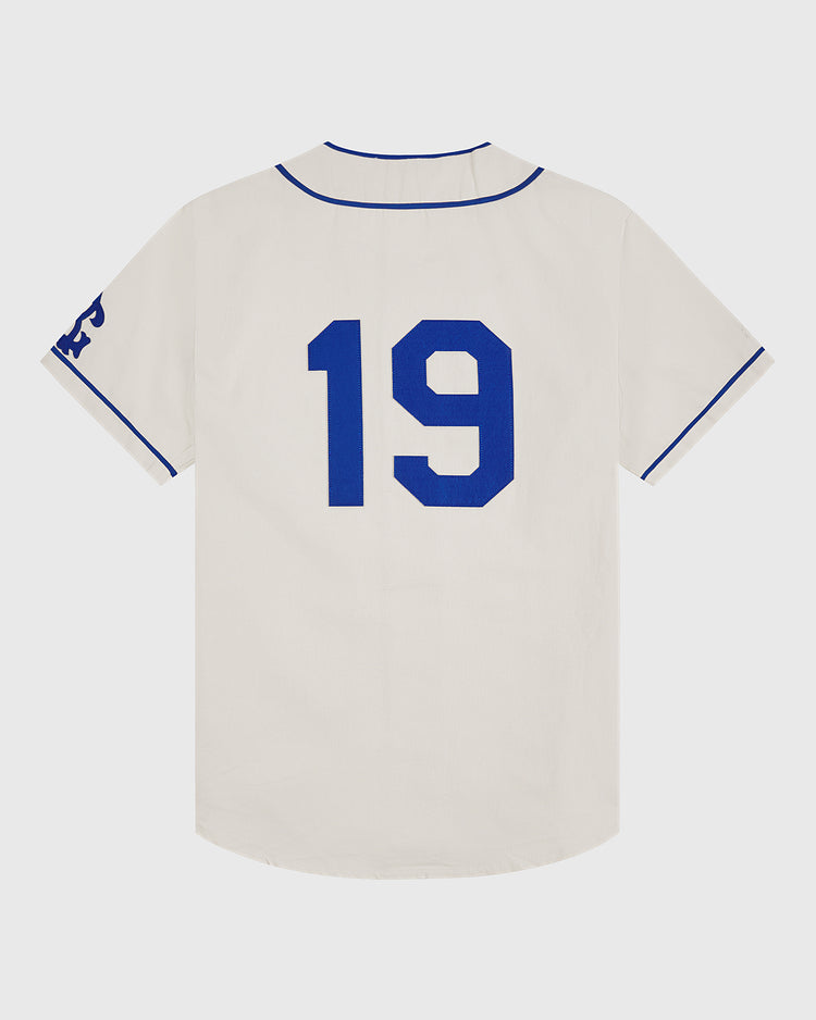 Showcasing vintage style, the Ebbets Field Brooklyn Royal Giants 1919 Cotton Twill Baseball Jersey is crafted in white cotton twill with blue trim and features the number 19 in blue on the back. Blue lettering accents the left sleeve, and the jersey is displayed flat against a white background, capturing the classic design of the original 1919 uniform.