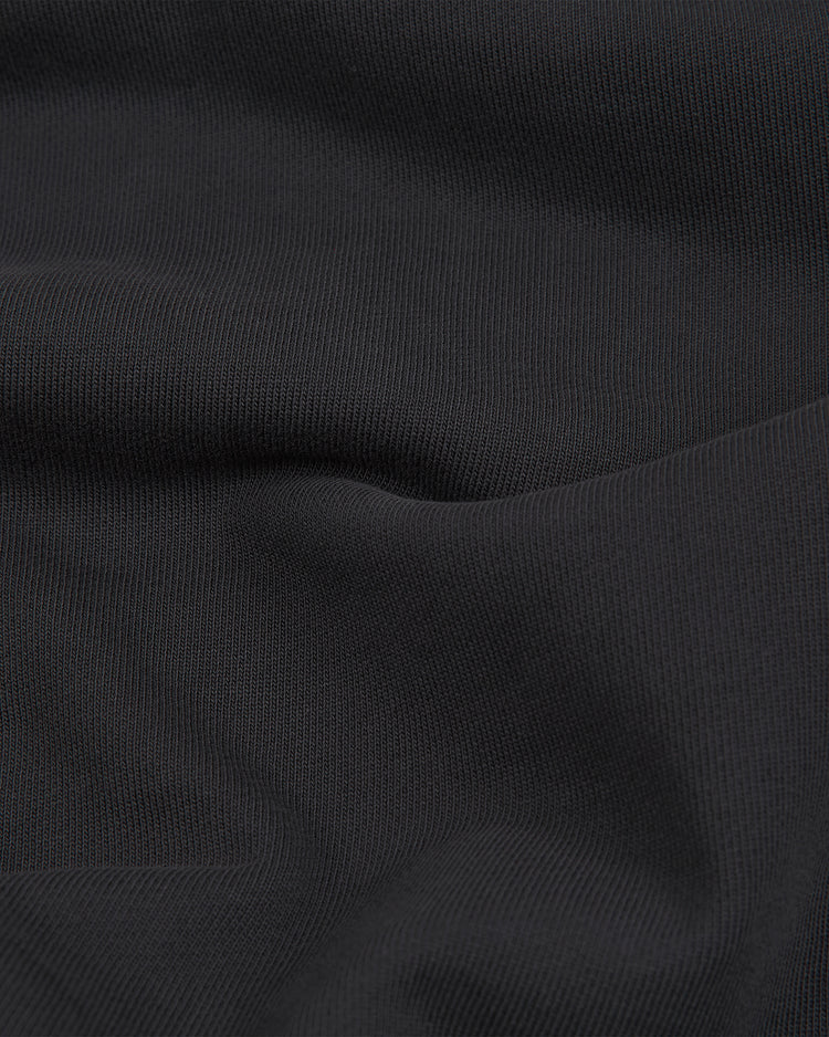Close-up of black fabric with a subtle, fine ribbed texture and gentle folds creating soft shadows—perfect for the Ebbets Field New York Cubans Heavyweight Cotton Terry Pullover Hoodie, inspired by classic Negro League apparel.
