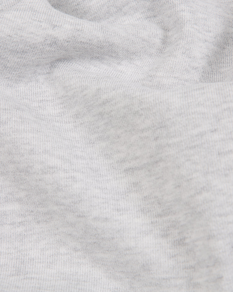 Close-up of light gray fabric with a subtle ribbed texture and gentle folds, casting soft shadows and highlights—typical of the heavyweight cotton used in the Ebbets Field Brooklyn Royal Giants Heavyweight Cotton Terry Pullover Hoodie, inspired by Black baseball history.