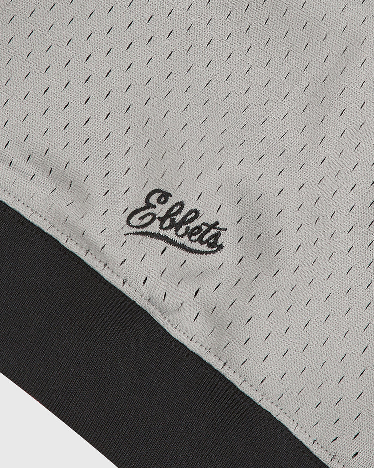 Close-up of the gray mesh fabric on the Ebbets Field Homestead Grays V-Neck Mesh Jersey, detailed with small perforations, black cursive Ebbets embroidery, and finished with a black ribbed trim—a design inspired by classic Negro Leagues Homestead Grays jerseys.