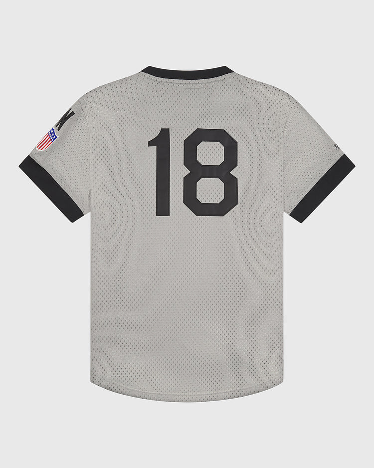 The Ebbets Field Homestead Grays V-Neck Mesh Jersey is a vintage-inspired short-sleeve sports jersey in gray, featuring a black collar and sleeve cuffs. The jersey displays the number 18 in black on the back and an American flag patch on the right sleeve, paying homage to the legendary Homestead Grays with an authentic Negro Leagues look.