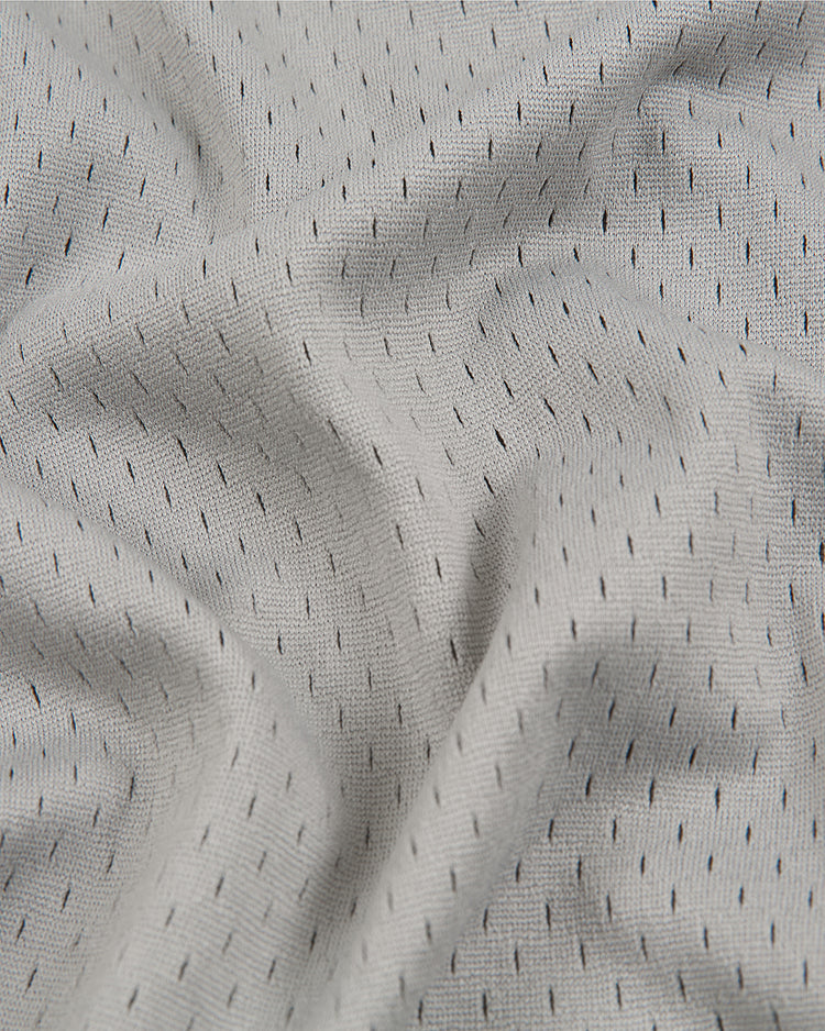 Crafted by Ebbets Field, the Homestead Grays V-Neck Mesh Jersey features a light gray mesh fabric adorned with delicate vertical black dashes, forming a subtle dotted pattern inspired by vintage baseball jerseys. The slightly wrinkled texture and gentle folds evoke the timeless style of the classic Homestead Grays jerseys from the Negro Leagues.