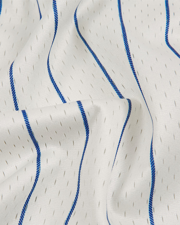 White textured mesh fabric featuring thin blue wavy stripes and small, evenly spaced gray dash marks, elegantly draped to highlight gentle folds and creases—capturing the enduring appeal of vintage baseball jerseys inspired by classic Negro Leagues apparel. Shown here: the Ebbets Field Brooklyn Royal Giants 1925 V-Neck Mesh Jersey.