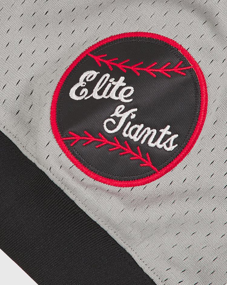 This Ebbets Field Baltimore Elite Giants 1949 V-Neck Mesh Road Jersey features a circular patch with red stitching and “Elite Giants” embroidered in white on a black background, sewn onto gray perforated fabric that echoes the classic mesh road jerseys worn by the 1949 Baltimore Elite Giants in the Negro League.