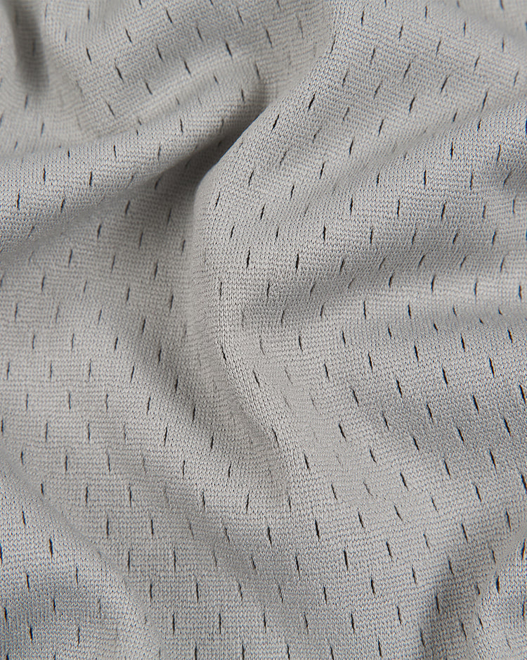 The Ebbets Field Baltimore Elite Giants 1949 V-Neck Mesh Road Jersey features a light gray textured fabric accented with small, evenly spaced black dashes in a regular pattern, capturing the subtle, modern design of classic sportswear. The mesh surface has a soft, slightly wrinkled appearance that offers both style and comfort, evoking the original road jersey’s timeless appeal.