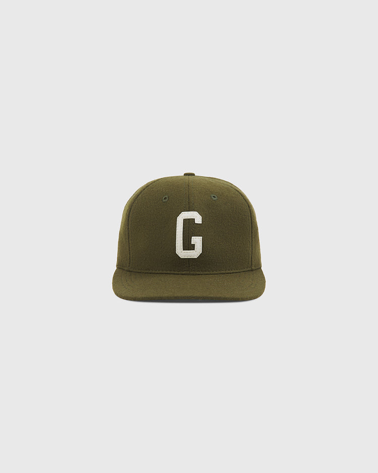 The Homestead Grays 1945 Authentic Wool Ballcap by Ebbets Field features an olive green wool design with a flat brim and a prominent white “G” embroidered on the front, shown against a plain light gray background.