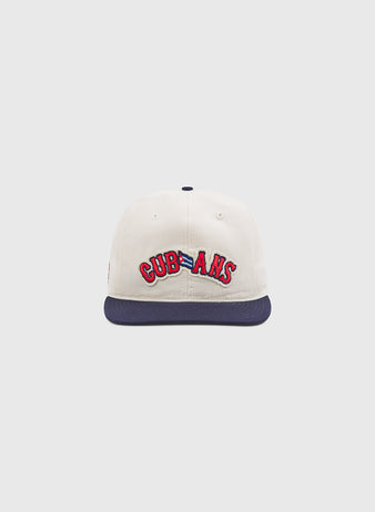 The Ebbets Field New York Cubans Authentic Cotton Ballcap features cream-colored cotton twill with a navy blue brim. The front displays “CUBANS” embroidered in red with a blue outline, honoring the historic New York Cubans from the Negro League. The background is plain and light gray.