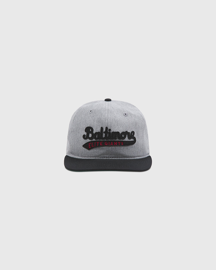 A plain, light gray background showcases the Ebbets Field Baltimore Elite Giants 1949 Cotton Twill Ballcap. This gray cap features a black brim and displays black cursive “Baltimore” text on the front above a bold red strip that reads “Elite Giants,” paying tribute to the historic Baltimore Elite Giants of Negro League baseball.