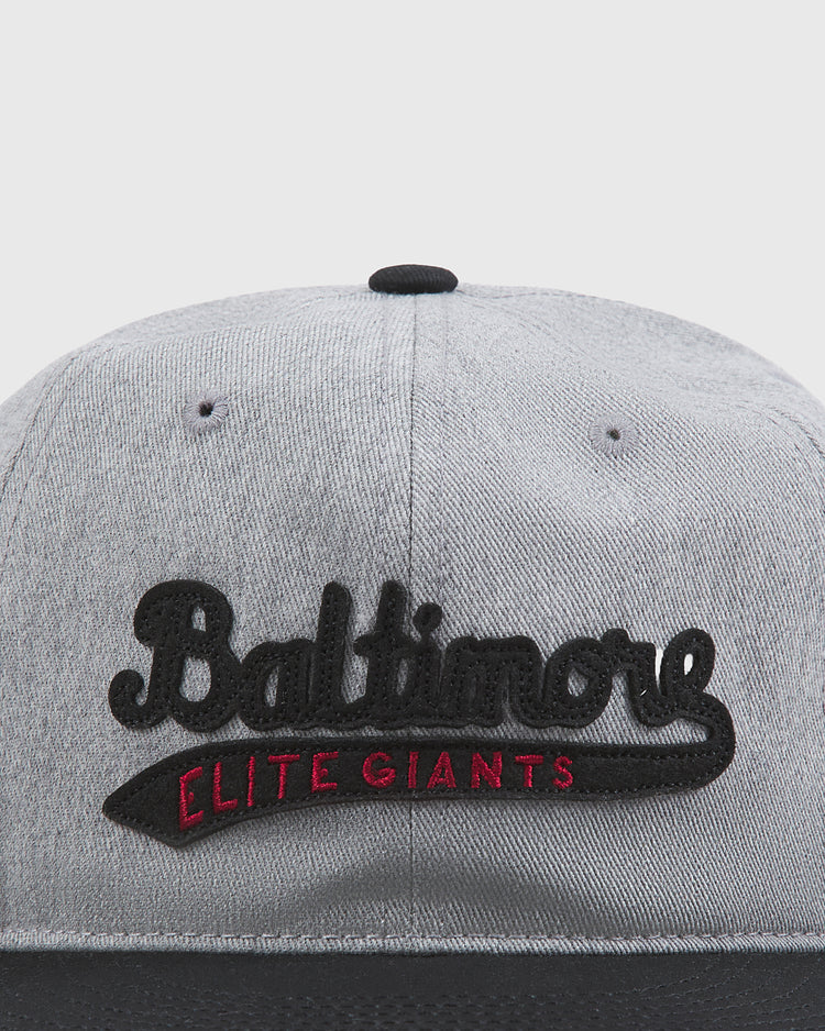 The Ebbets Field Baltimore Elite Giants 1949 Cotton Twill Ballcap features gray cotton twill with black stitching. The front showcases “Baltimore” in bold black letters, with “Elite Giants” in smaller red lettering beneath, paying tribute to the legendary Baltimore Elite Giants of the Negro League.