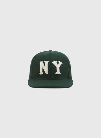 The Ebbets Field NY Black Yankees Authentic Wool Ballcap, featuring a dark green wool construction and bold white “NY” lettering on the front inspired by the New York Black Yankees of the Negro National League, is displayed against a plain light gray background.