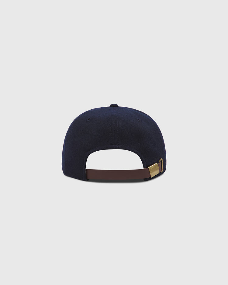 A rear view of the Brooklyn Royal Giants Authentic Wool Ballcap by Ebbets Field, shown in navy blue with a brown adjustable strap and brass buckle, set against a plain light gray background.