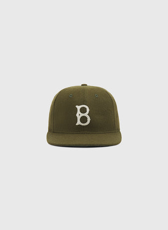 The Brooklyn Royal Giants Authentic Wool Ballcap by Ebbets Field is an olive green wool cap with a white embroidered letter B on the front, inspired by the Brooklyn Royal Giants and celebrating Black baseball history, shown against a plain light gray background.
