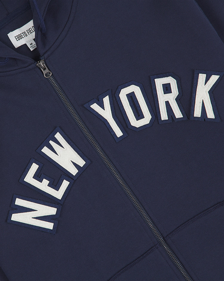Black Yankees Heavyweight Cotton Terry Full-Zip Hoodie from Ebbets Field, featuring NEW YORK in white and blue letters across the chest. Inspired by classic Negro League apparel, this heavyweight full-zip hoodie includes a white EBBETS FIELD tag near the collar, blending style with a tribute to baseball history.