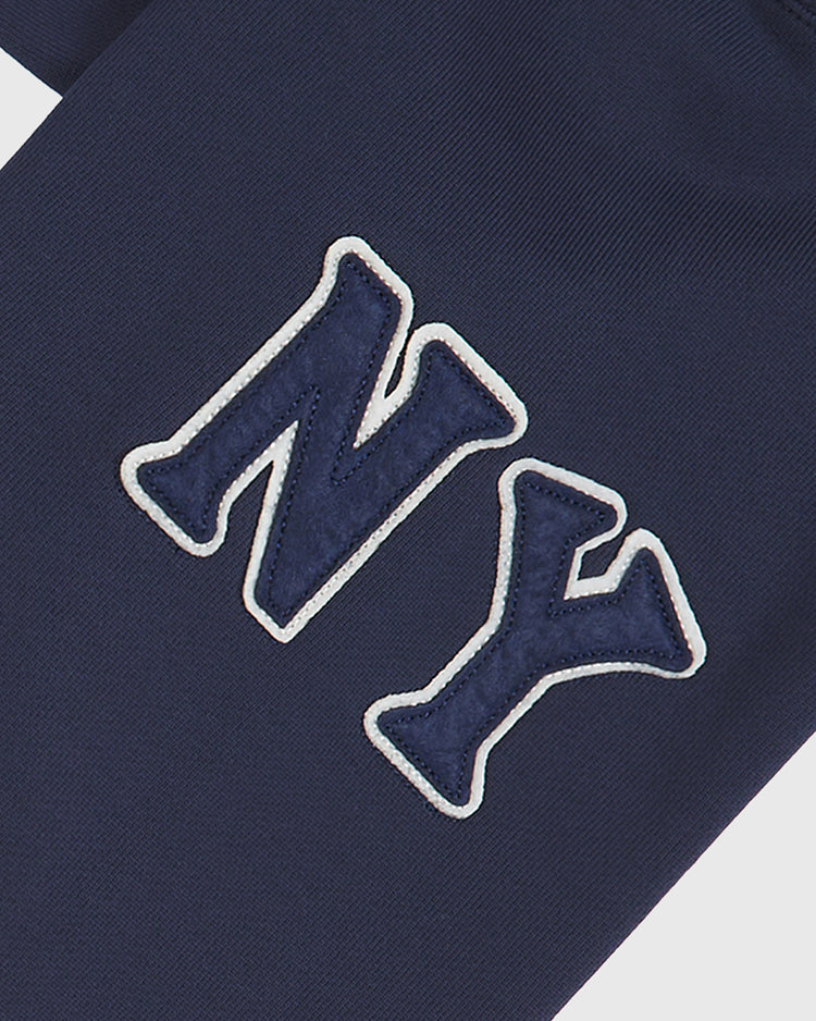 Close-up of dark blue fabric featuring large embroidered “NY” letters with a white outline—an iconic detail inspired by New York sports teams and seen on the Ebbets Field Black Yankees Heavyweight Cotton Terry Full-Zip Hoodie.