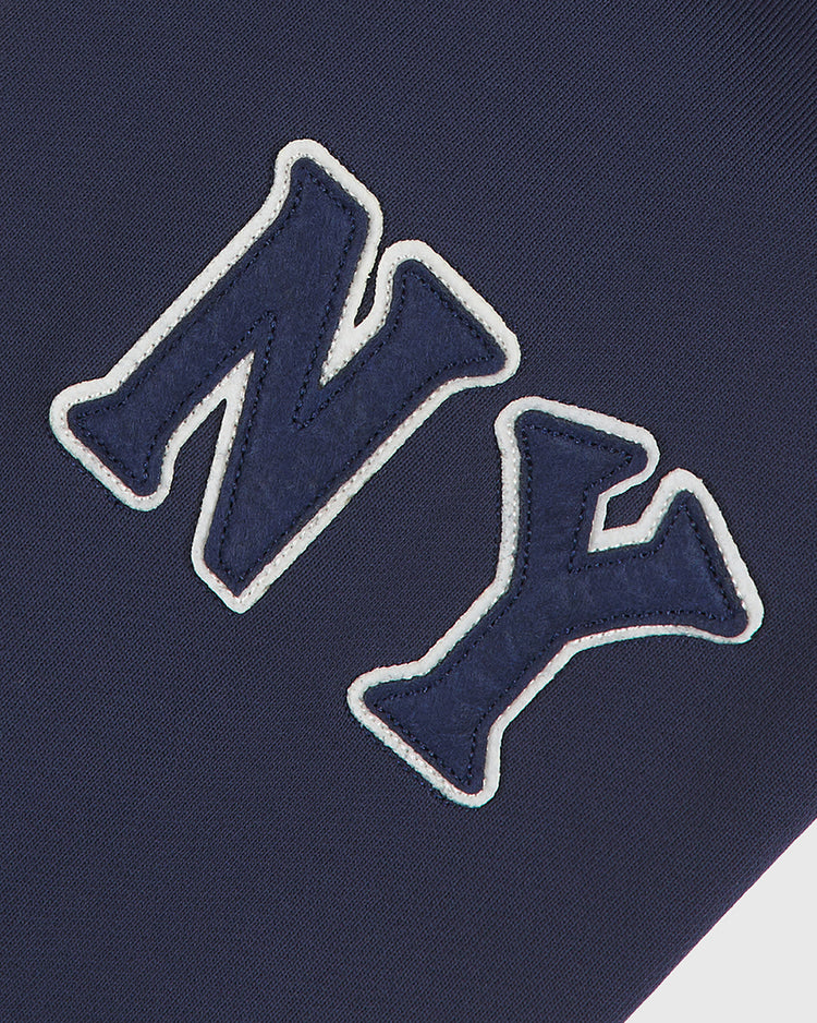 The Ebbets Field Black Yankees Heavyweight Cotton Terry Full-Zip Hoodie features navy blue fabric accented by large, dark blue “NY” letters outlined in white, sewn diagonally across the front—evoking the iconic style of classic Negro League apparel. This hoodie embodies vintage NY Black Yankees spirit with its bold and timeless design.