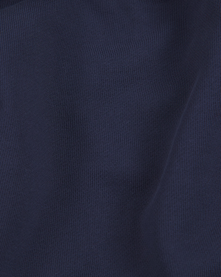 Close-up of dark blue fabric with a fine knit texture and soft folds, revealing subtle highlights and shadows—capturing the premium look of our Ebbets Field Black Yankees Heavyweight Cotton Terry Full-Zip Hoodie.
